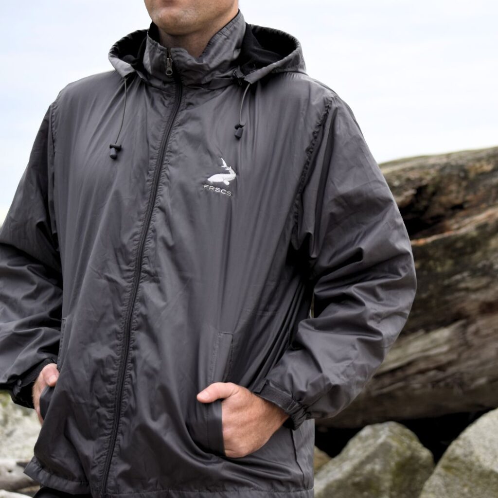 Grey Men's Aquastop Wind Breaker with the FRSCS Logo on the Left Chest. Model has hands in the jacket pockets